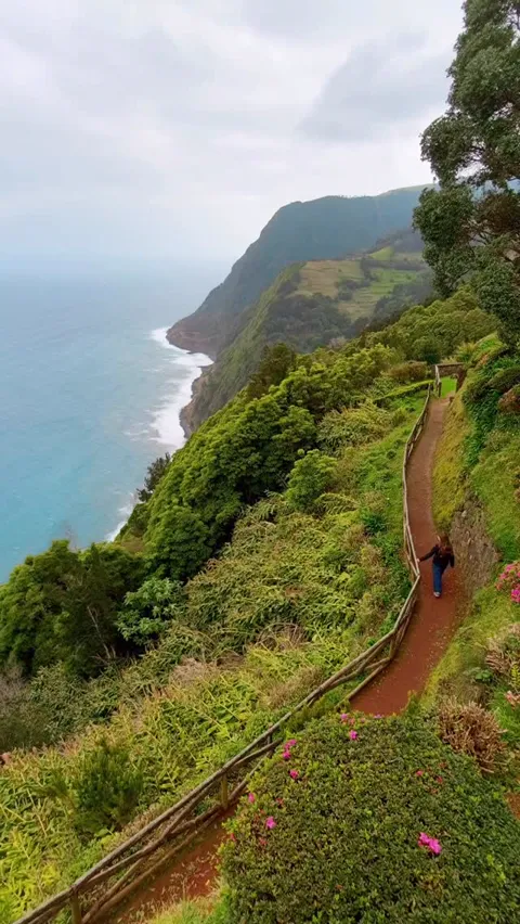A narrow footpath cut into a green clifftop high above the Atlantic, Azores