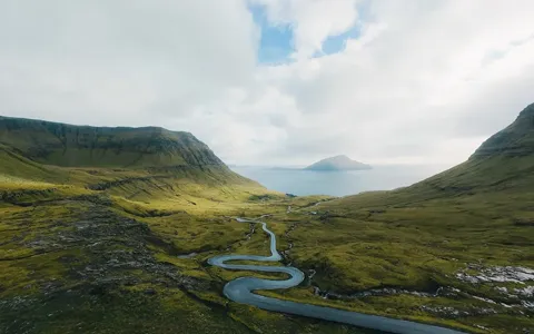 A river winding through a green valley out toward the fjord, Faroe Islands