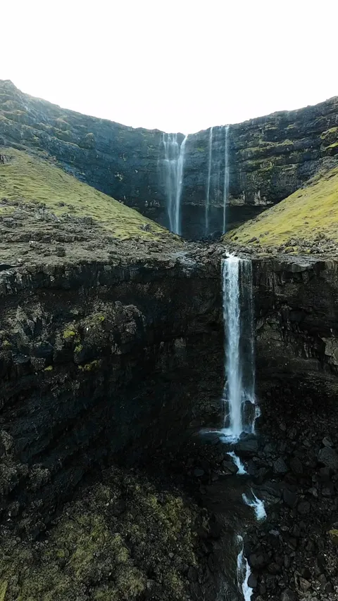 A tall waterfall falling through a green bowl down toward the sea, Faroe Islands