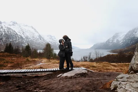 Kristi Leka on a boardwalk with snow-covered mountains rising across the water behind