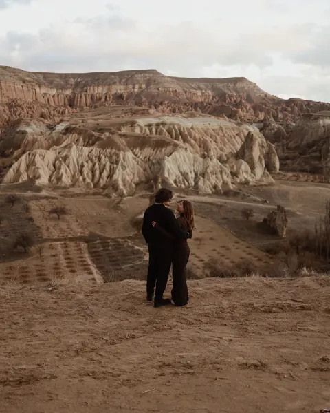 Kristi Leka standing on eroded, terraced badlands under a pale sky