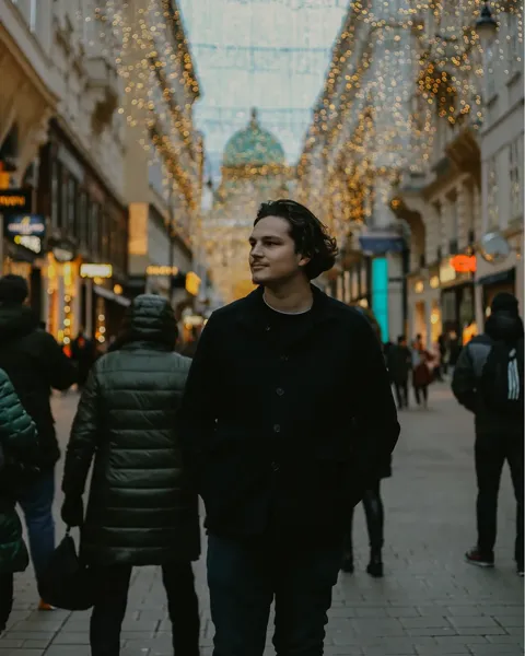 Portrait of Kristi Leka walking down a shopping street strung with Christmas lights
