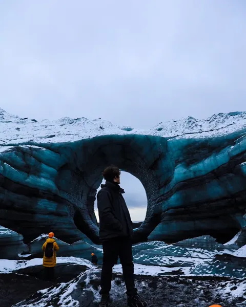 Kristi Leka standing at the mouth of a blue glacier ice cave