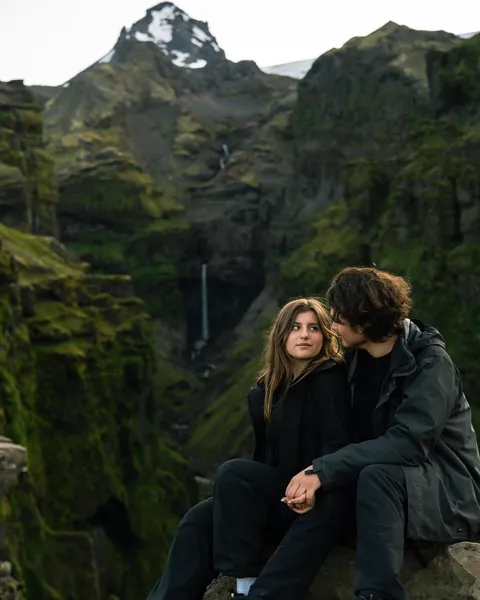 Kristi Leka sitting in a green mossy gorge below a snow-capped peak