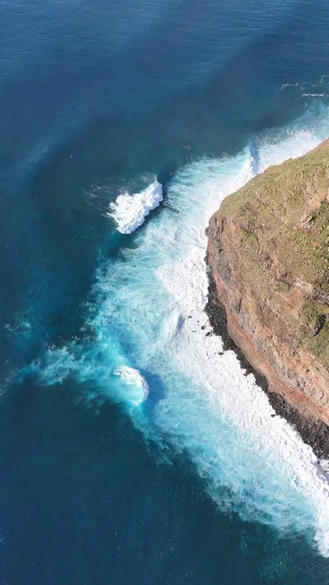 Aerial view of waves breaking turquoise against dark cliffs, Madeira